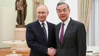 Президент России Владимир Путин и министр иностранных дел Китая Ван И обмениваются рукопожатием во время встречи в Кремле в Москве.